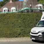 Camionnette de l'entreprise Batidom Rénove garée le long d'une haie